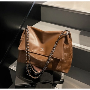 Detail of dark brown leather tote bag with chain strap and printed bird logo design