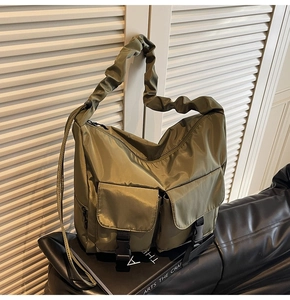 Detail of army green nylon shoulder bag with ruffled strap and large buckle pockets