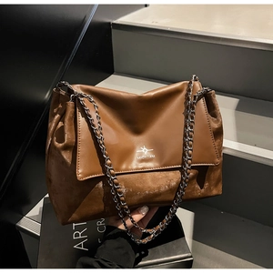 Detail of vintage brown tote bag with dual chain straps and mixed leather textures
