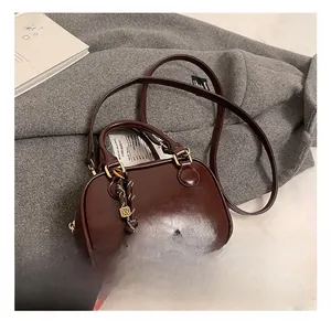 Detail show of dark brown glossy pillow bag with metal logo and woven strap charm