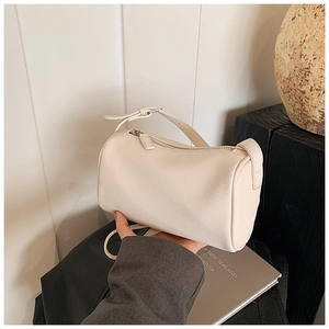 Détail du sac polochon crème montrant la texture du cuir grainé et les finitions soignées