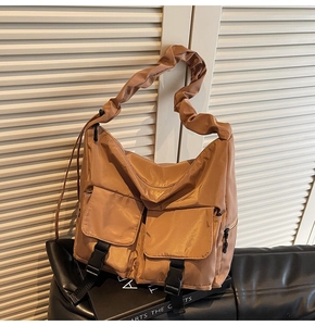 Detail of khaki nylon tote bag with ruched shoulder straps and dual front buckle pockets