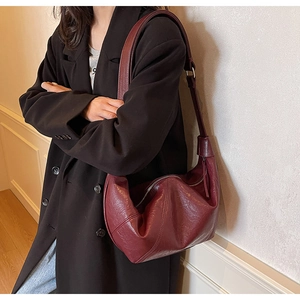 Detail view of burgundy hobo bag with oil-wax leather texture and adjustable strap