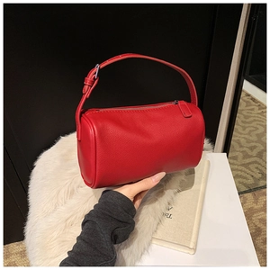 Détail de la texture cuir grainé rouge vif sur un sac polochon cylindrique moderne