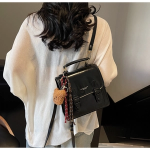 Detail der schwarzen Vintage-Ledertasche mit Bärenanhänger als Umhängetasche getragen