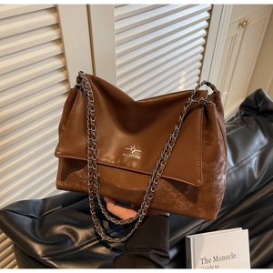 Detail of dark brown leather tote bag with silver MICHTAM logo and metal chain strap