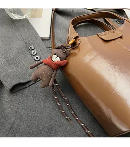 Close-up of brown leather bucket bag with cute bear charm on a dark grey blazer