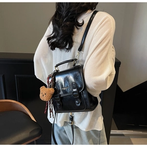Rückansicht eines glänzenden schwarzen Vintage Rucksacks mit Bärenanhänger am Modell