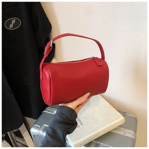 Détail du sac polochon rouge en cuir avec fermeture éclair argentée et grain de cuir