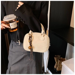 Detail of beige Boston handbag with matte finish and creative bell charm accessory