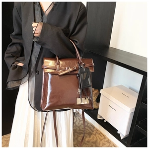 Détail d'un sac à main en cuir verni marron avec plaque dorée et porte-carte amovible
