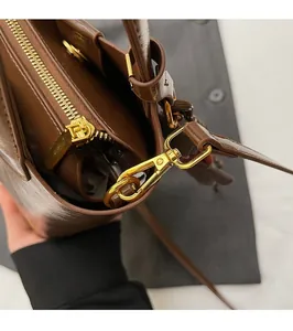 Close-up of premium gold-tone zipper and hardware on a brown leather bucket bag