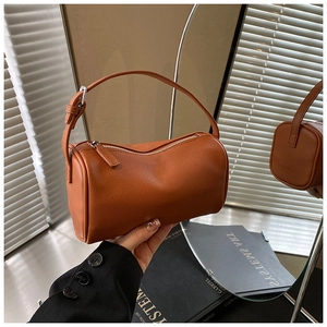 Détail de la texture en cuir marron d'un sac cylindre avec zip argenté et poignée large