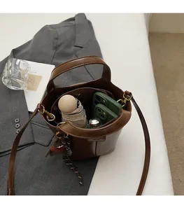 Top view of brown bucket bag interior showing capacity with phone, umbrella and perfume