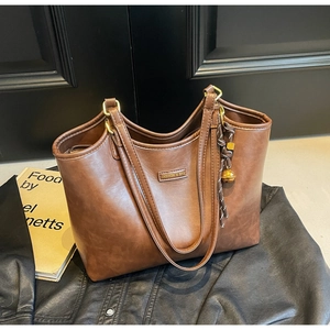 Detail einer großen braunen Shopper-Tasche mit Retro-Ölwachs-Textur und Gold-Logo