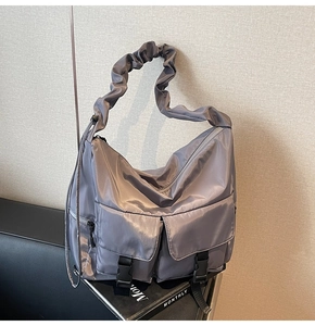 Detail of grey nylon tote bag showing cargo pockets with buckles and ruffled strap