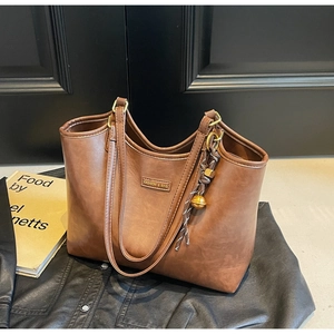 Detailaufnahme der braunen Ledershopper mit goldenem Anhänger auf einer Lederjacke