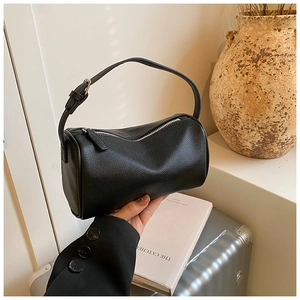Gros plan d'un sac boston noir en cuir grainé avec une bandoulière réglable