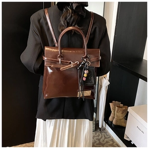 Détail du sac à dos en cuir marron foncé brillant avec breloques et sangles réglables