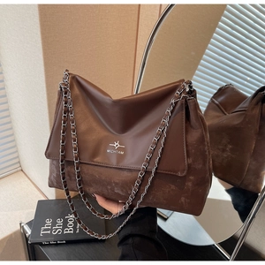 Detail of vintage brown tote bag showing smooth leather flap and silver chain strap