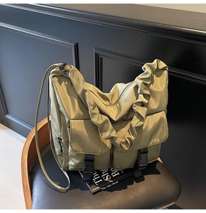 Detail of army green nylon tote featuring buckle pockets and ruffled shoulder strap