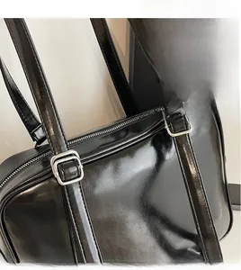 Detail of adjustable straps and silver metal buckles on a black patent leather tote bag