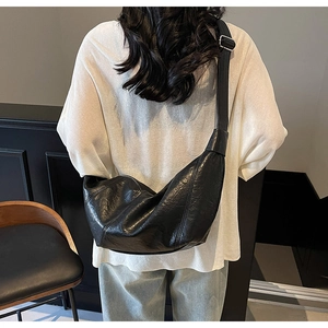 Rear view of model wearing a black pleated leather croissant bag with wide strap