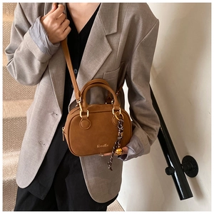 Close-up of caramel brown leather shoulder bag with gold buckles and silk scarf detail