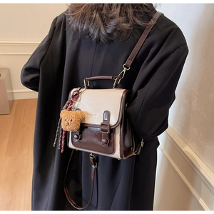 Nahaufnahme eines Retro-Rucksacks in Creme und Braun mit süßem Bärenanhänger aus Plüsch