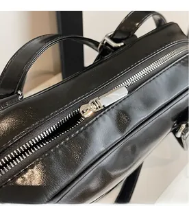 Close-up of smooth silver metal zipper and hardware on black patent leather shoulder bag