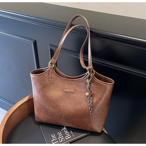 Detail einer braunen Shopper Tasche mit Fashion & Bag Logo und gewebtem Knoten-Anhänger