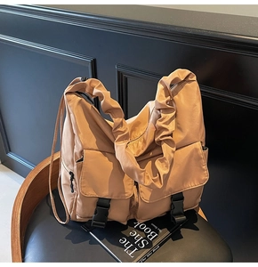 Detail of oversized nylon tote bag featuring ruched wide straps and buckle flap pockets