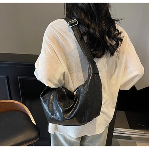Detailed view of black textured leather hobo bag with adjustable wide silver buckle strap