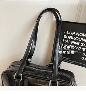 Side view of black glossy patent leather tote bag with silver zippers and long handles