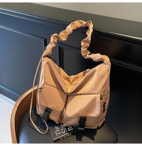 Detail of khaki nylon tote bag with pleated wide strap and dual utility buckle pockets