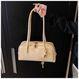 Macro detail of beige PU leather shoulder bag with gold padlock and key charm