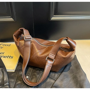 Detail of dark brown croissant bag with vintage leather texture and wide shoulder strap