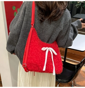Detail of red plush shoulder bag with a large white bow on model in a cozy setting