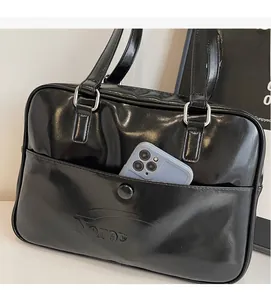 Close-up of black patent leather tote bag showing external pocket and metallic rings