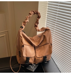 Close-up of caramel nylon tote bag featuring ruffled cloud handle and utility buckle pockets