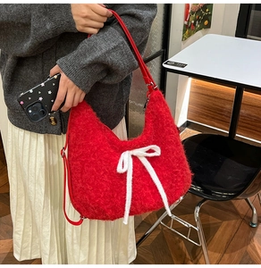 Close-up of fluffy red plush tote bag with white bow knot detail and leather handle