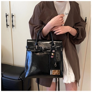 Détail d'un sac à dos en cuir noir brillant avec des finitions dorées et un porte-cartes