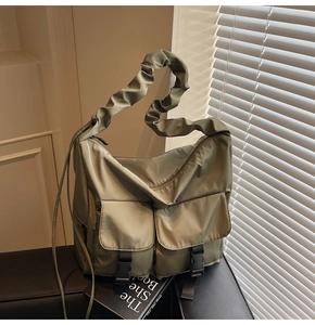 Detail of olive green nylon tote bag featuring ruffled shoulder straps and buckle pockets