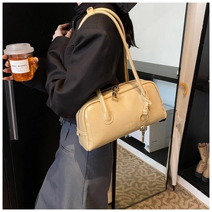 Macro detail of beige glossy leather Boston bag with metal lock and logo engraving
