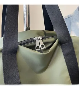 Détail de la double fermeture éclair en métal argenté sur un sac fourre-tout en nylon vert
