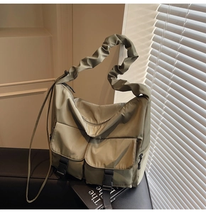 Detail of olive green nylon tote bag with ruched cloud strap and tactical buckle pockets