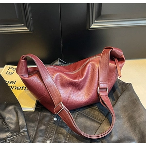 Detailed view of deep red faux leather texture and silver buckle on hobo bag