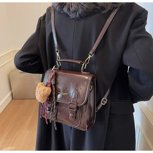 Detailansicht eines dunkelbraunen Vintage-Rucksacks aus Leder mit Plüschbären-Anhänger