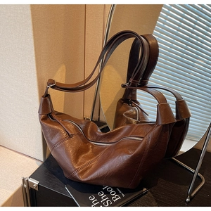 Detailed close-up of dark brown crescent bag with retro leather texture and adjustable strap
