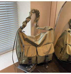 Detail of olive green nylon tote with buckled pockets and pleated wide shoulder strap